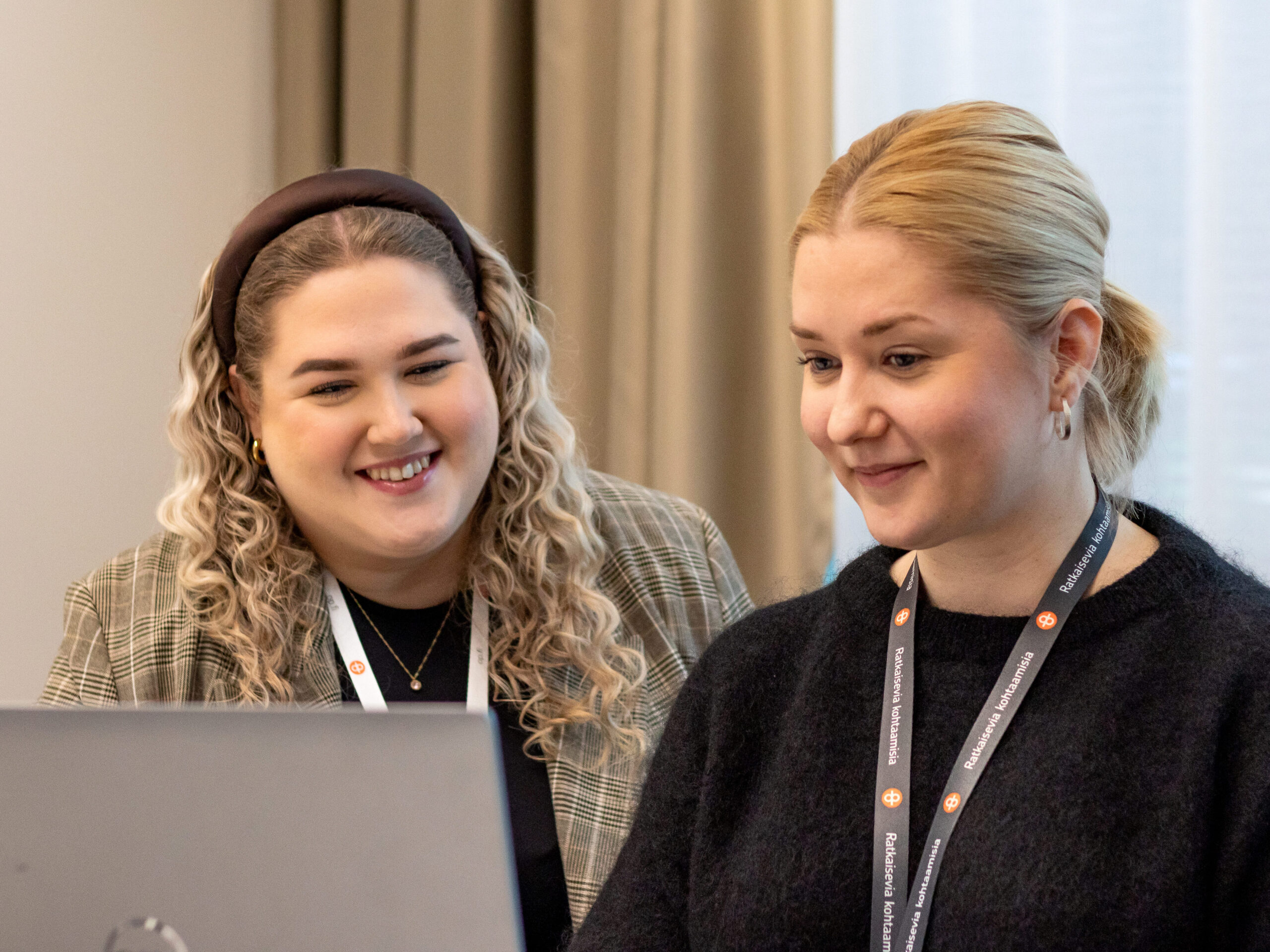 Two people look down and smile at the laptop screen.