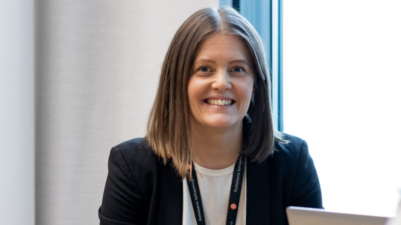 Henkilö istuu pöydän ääressä ja katsoo kameraan