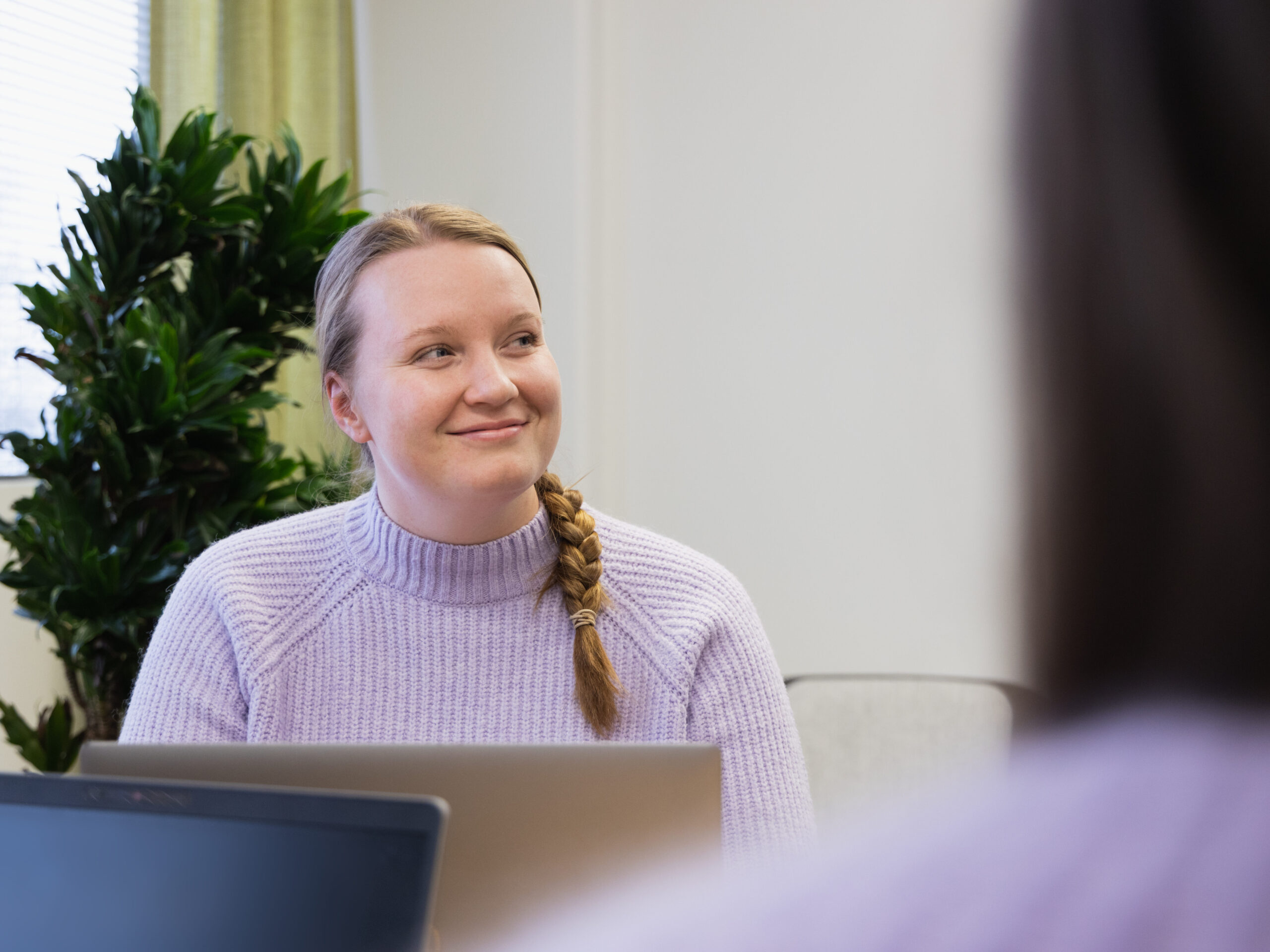 Violettipaitanen henkilö hiukset letillä katsoo sivulle