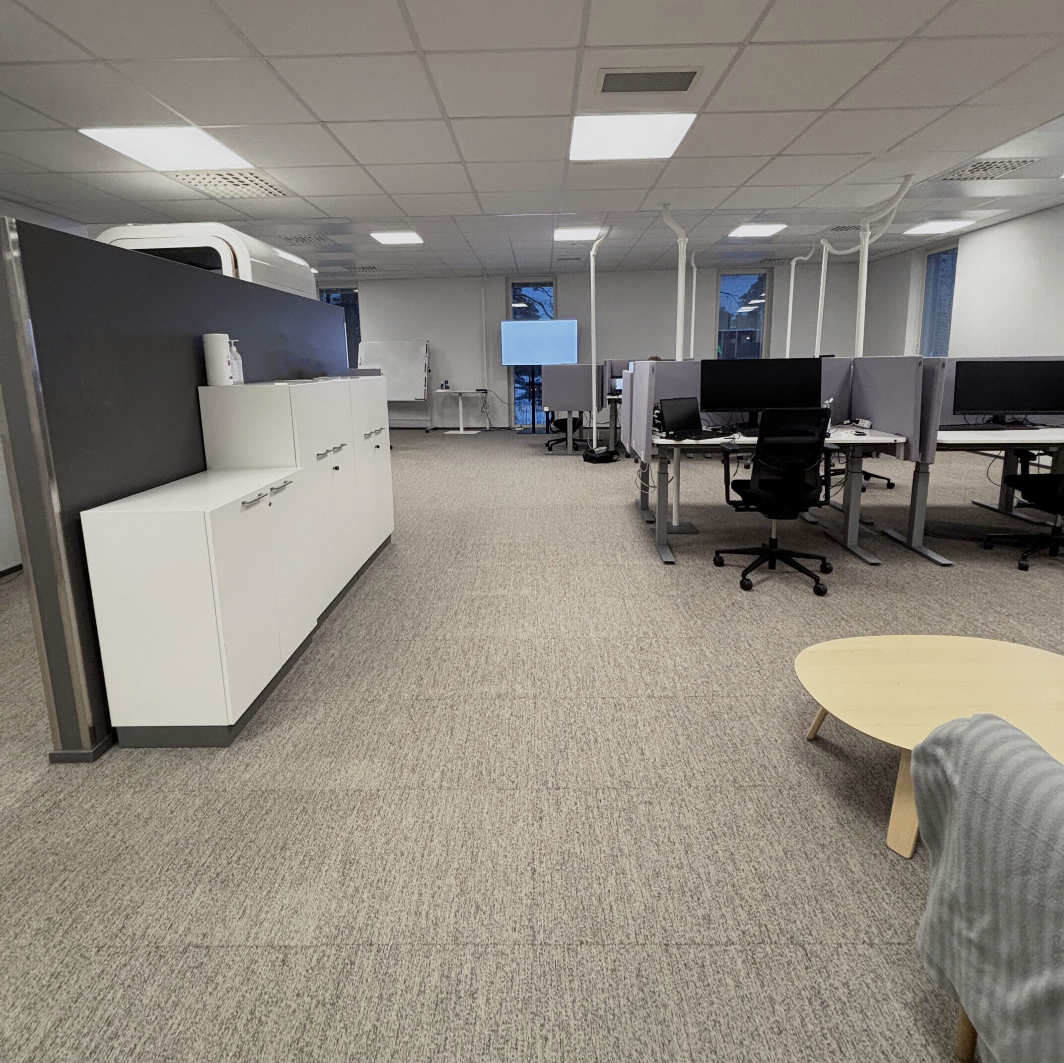 Tribedo Oulu avoin toimistotila, jossa työpisteitä, sermillä rajattuja alueita ja vaaleasävyinen sisustus.