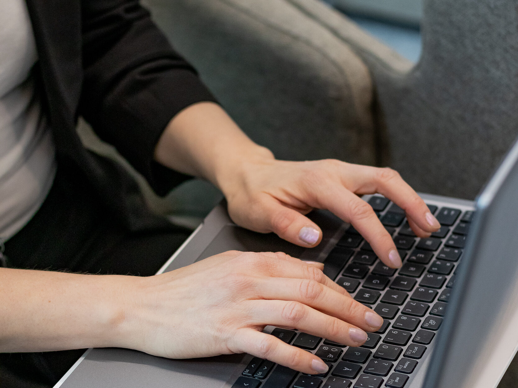 Meri työssään Tribedon Taustapalveluissa. Lähikuva käsistä kannettavan tietokoneen näppäimillä.