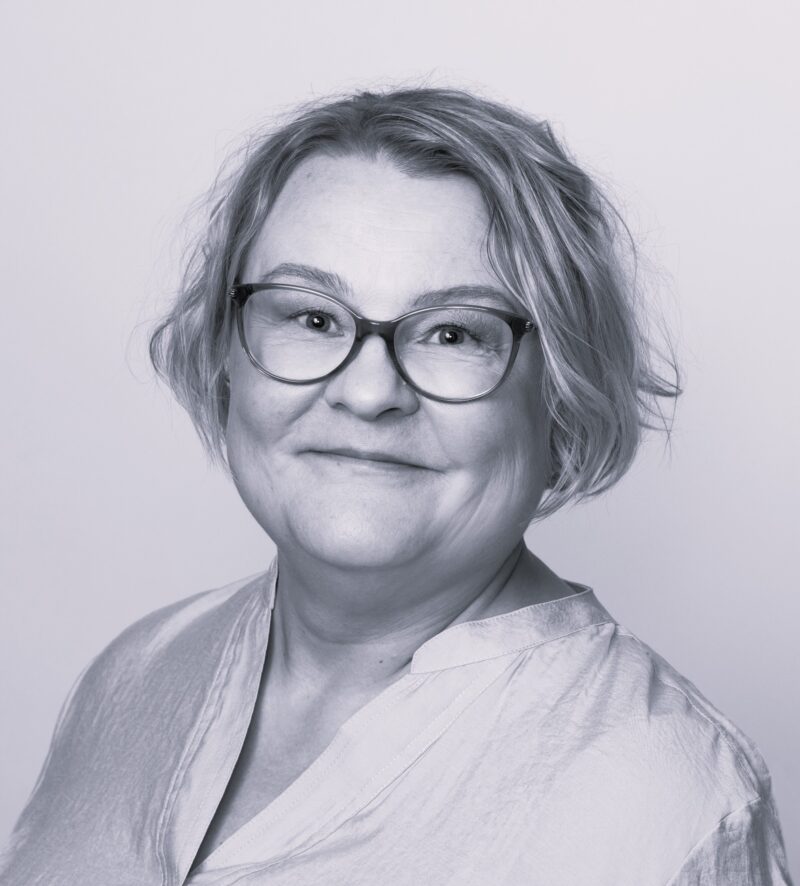 Mustavalkoinen kasvokuva Vuoden tribedolainen 2025 Tanjasta. Lyhyehköt hiukset ja mustareunaiset silmälasit.